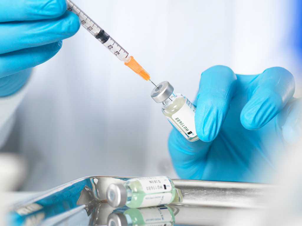 Image of person withdrawing medication from a vial with a needle.