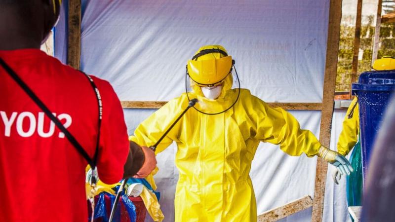 In this file photo taken Thursday, Oct. 16, 2014, a healthcare worker in protective gear is sprayed with disinfectant after working in an Ebola treatment center in the west of Freetown, Sierra Leone