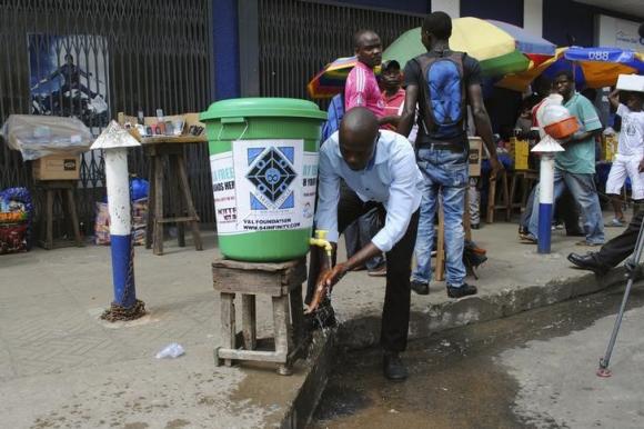   A man washes his hands as a preventive measure against the Ebola virus on a street in Monrovia, September 13, 2014.  Credit: Reuters/James Giahyue