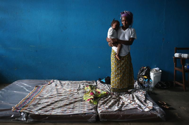 A mother and child stand atop their mattresses in a classroom now used as Ebola isolation ward on Aug. 15, 2014, in Monrovia, Liberia