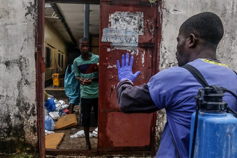 A health worker guards the door as a patient who escaped is escorted back inside at the Redemption Hospital holding center in Monrovia. by Tim Freccia
