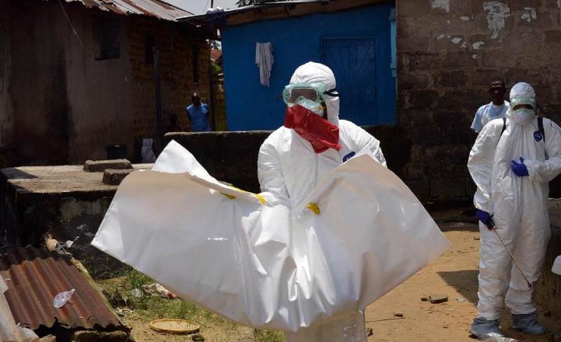 Liberian Red Cross health workers, wearing protective suits, carry the body of a 18-old-month baby (AFP Photo/Zoom Dosso)