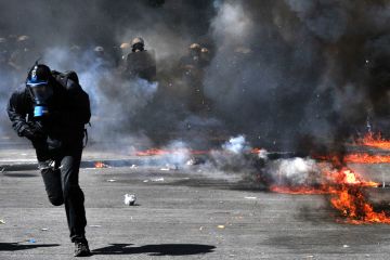 A protester runs from police in Athens on Wednesday. (Louisa Gouliamaki/AFP/Getty Images)
