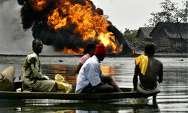 Niger delta residents pass a burning Shell oil pipeline as they evacuate their homes by boat in December 2005. (Photo: George Osodi/AP) 